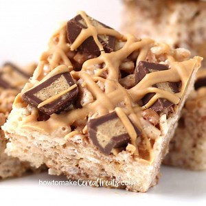 That's peanut butter fudge on top of those gooey Reese's Cup Rice Krispie Treats. Oh, yeah! They are so amazingly good you won't be able to eat just one. Recipe - https://howtomakecerealtreats.com/reeses-cup-rice-krispie-treats/ | Hungry Happenings