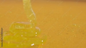 Healthy organic honey. Sweet fresh golden honey pouring on the yellow glass background, thick honey dripping from above.