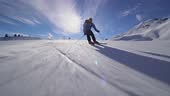 Professional skier skiing on slopes in the Swiss alps. Sun rays and...