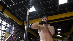 Close-up of muscular man with a bare torso training on a rotating boxing machine