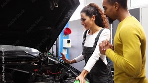 Young female auto mechanic explaining to her customer what needs to be fixed in his car