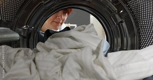 A broken washing machine. Women Housewife takes out laundry and a broken element the washing machine. Woman has problem with washing machine. View Looking Out From Inside Washing Machin