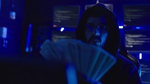 Male hacker counting money at hacking room. He got a lot money from hacking system. Hacker concept.
