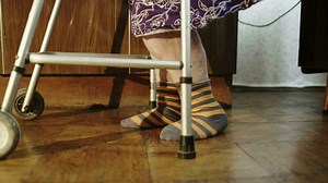 Elderly woman going slowly with the help of walker