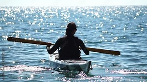 Woman sea kayak. Happy smiling woman in kayak on ocean, paddling with wooden oar. Calm sea water and horizon in background. Active lifestyle at sea. Summer vacation.