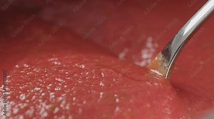 Slow motion check viscosity of tomato soup puree with spoon macro shot