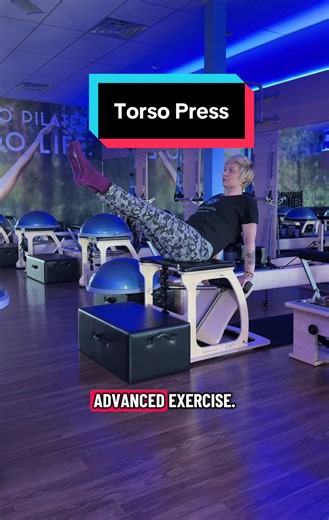 Make sure you have a solid foundation. I’ve been practicing pilates for some time before we move into this advanced exercise using the chair. We have one spring on set to number three. My arms are shoulder distance on the pedal. We have our short box right in front of the chair to give our feet an anchor point anytime we need it. I build in layers to see how my body is feeling as I build through those layers. I’m gonna notice if that’s stability is not available to me today before I move forward