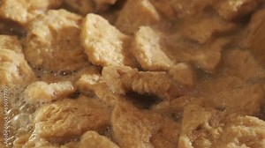 Close up view of cooking vegan TVP Textured Vegetable Protein in a pan, in slow motion 4K
