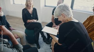 Group of corporate professionals laughing during team building training session in the office. Coach using a digital tablet with the multi-ethnic business team sitting in a circle.