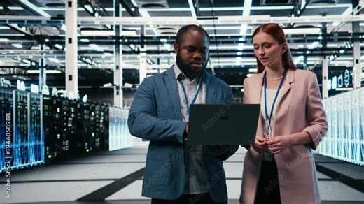 Doing maintenance, laptop and engineering team in server hub working together to finish tasks. Configuring settings, servers and teamworking colleagues in modern high tech data center, camera A
