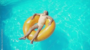 Kid lies on an inflatable ring in the pool. Little girl Swimming In Pool on orange inflatable rubber ring. Holidays, Vacations, Recreations, Sport, Children, Water, Hotel, Summer