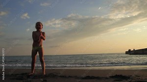 Little girl doing cartwheel on the beach on the beautiful sunset. Silhouette, fisherman