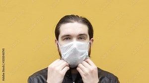 man puts on and removes a disposable mask to protect against the coronavirus.Instructions how to properly wear a respirator and mask,protect your loved ones with self-isolation and safety precautions