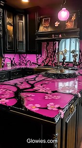 This kitchen has pretty pink cherry blossom flowers inside the countertops, made with shiny resin. The black accents around the counters make the pink flowers pop and look super cool. It’s like having a beautiful garden right in your kitchen!The mix of soft flowers and bold black colors makes the kitchen look fun and exciting. It’s a great place to cook, eat, and spend time with family. This kitchen is both pretty and powerful, all at the same time! | Monique Lula