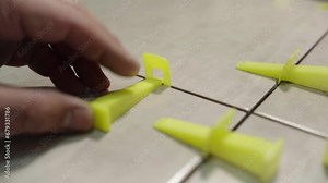 the master levels the tiles when laying them on the floor using plastic wedges