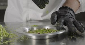 Kunefe or kunafa traditional Turkish dessert. Pastry chef pour shredded pistachios in the copper plate. Arabic sweets. Middle eastern national food desserts