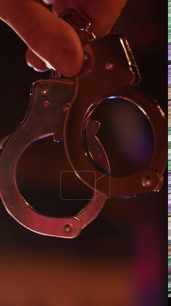 A detailed closeup shot of handcuffs being held in a firm grip, illuminated by the vibrant and colorful police lights Stock Video Footage - Alamy