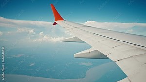 Wing of flying over ocean and island airplane from window on clouds in blue cloudy sky. Aircraft wing in sunny weather in tropics. Passenger jet flight. Travel, tourism, journey, trip, wanderlust.