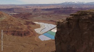 A spectacular 4K drone shot of the Potash Evaporation Ponds in Moab, Utah. The dazzling, electric blue water at this mining facility lies in stark contrast to the red desert landscape surrounding them