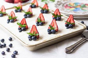 A festive Sour Cream Cake topped with silky whipped cream cheese frosting. Fresh strawberries and blueberries make this beautiful low carb dessert a standout! Recipe --> https://www.lowcarbmaven.com/sour-cream-cake-keto-low-carb/ | Low Carb Maven