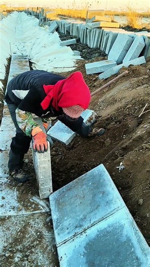 A Worker Carefully Installs Concrete Panels to Line a Canal