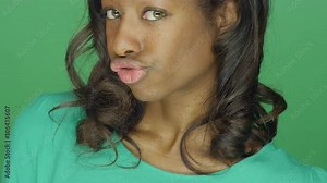 Beautiful African American woman making silly faces and a fish face, on a green screen studio background