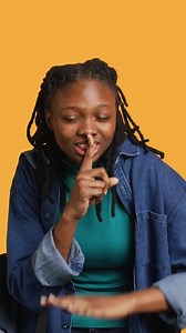 Vertical Stern african american woman doing shushing hand gesturing, irritated by noise, having negative mood. Girl placing finger on lips, doing quiet sign gesture, studio background, camera A