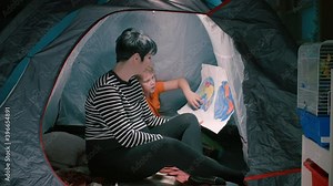 A pregnant mother with her son sitting in a tent looking at a homemade map of the world. Home education in self-isolation.