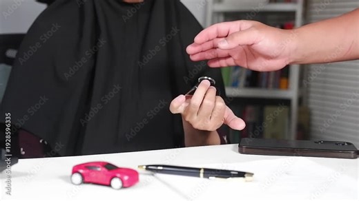 The handover of car keys between the seller and buyer, followed by a handshake. The agreement in the sale and purchase.