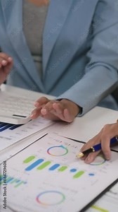 Business professionals collaborate, analyze financial charts and graphs at a conference table. Teamwork, data analysis, and brainstorming in progress