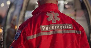 Back, man and paramedic walking to ambulance for emergency, ems service and healthcare in city. Rear view, medical professional and doctor outdoor at night for first aid, rescue operation and work