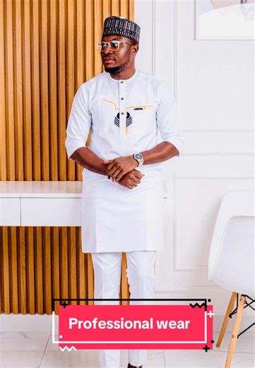#creatorsearchinsights Professional wear. Gemini prompts. Use the uploaded image as the facial and body reference. Recreate the exact pose, styling, composition, and environment in a high-end professional fashion editorial shoot. Scene setup: Full-body portrait of a stylish African man standing indoors in a modern minimalist interior. He is leaning slightly backward against a sleek white floating console table. His hands are clasped loosely in front of him at waist level. His head is turned slig