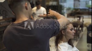 Hairstylist drying brunette hair with dryer while woman hairstyle in hairdressing salon. Hairdresser using dryer while female hairstyle. Professional hairstyling long hair in beauty salon.