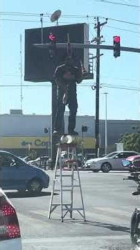 Malabarista callejero arriba de una escalera parado sobre un tubo y una tabla sobre puesta