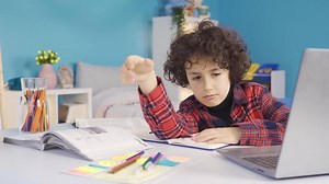 Tired boy falling asleep while doing homework. A male student studying in his room can't stand the tiredness and lack of sleep and falls asleep.