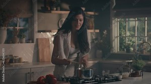 Pretty woman cooking soup on stove at kitchen. Close up of housewife preparing dinner at home. Young woman tasting soup on spoon at modern kitchen in slow motion, talking on phone, taking photos