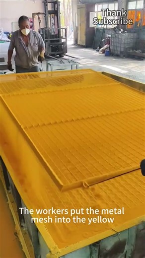 Workers put the metal mesh into the yellow plastic dipping pool for plastic dipping