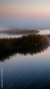 vertical 9:16 Layers of fog moving across a still pond in soft pastel-colored light