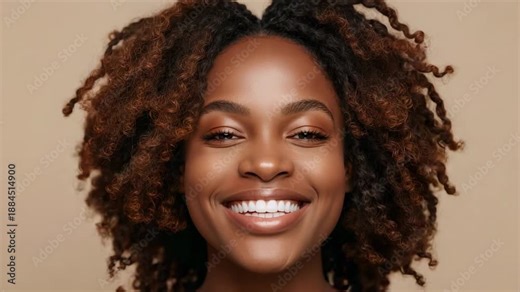 Smiling model with curls laughing settling to smile as camera rolling for portrait bare shoulders