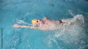 Underwater view of professional swimmer training in swimming pool, 4k 120 fps super slow motion raw video. Triathlete swim in black wetsuit