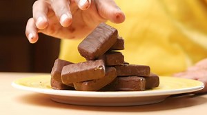 Download A person is stacking chocolate bars on a plate for free