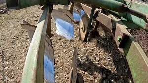 Close up on disc and chisel of plow as farmer moves plow to the field; farmer is preparing field for planting; concepts of farming and land management
