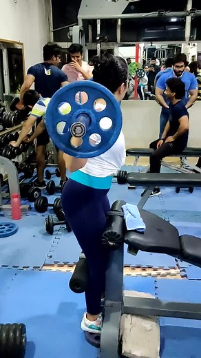 Women Squatting with Barbell at a Gym