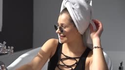 Young caucasian woman with towel on head and sunglasses getting spa...