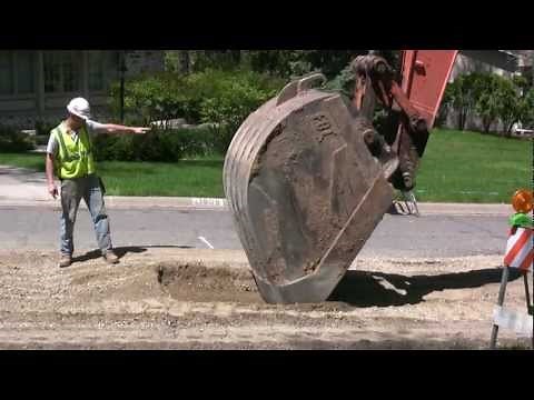 EXCAVATOR EXPOSES STORMSEWER -- REMOVES COVER