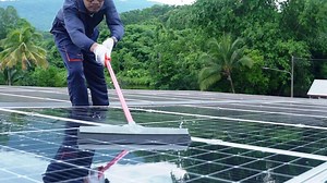Download A Technician performing maintenance on solar energy Clean the solar panels with a brush at the solar power plant. for free
