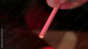Man lighting a cigarette and smoking at a table in bar with red light. He has problems. Stock Video