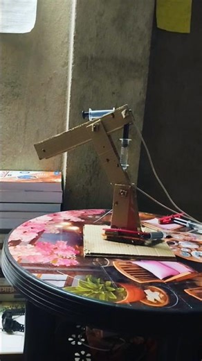 This item is a DIY hydraulic excavator model constructed from cardboard and syringes