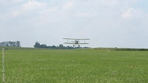 Ultra light bi-Plane take off and airborne on green fields in the countryside