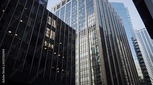 Skyscrapers and office buildings in New York City lower Manhattan's Financial Districit. Low angle view. Multiple buildings mostly modern with glass. Subtle camera pan.